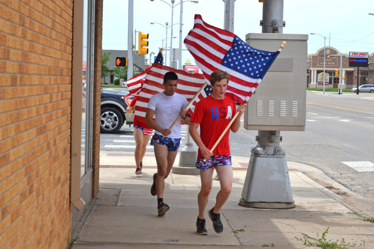 Young men run with U.S. flags through Dumas